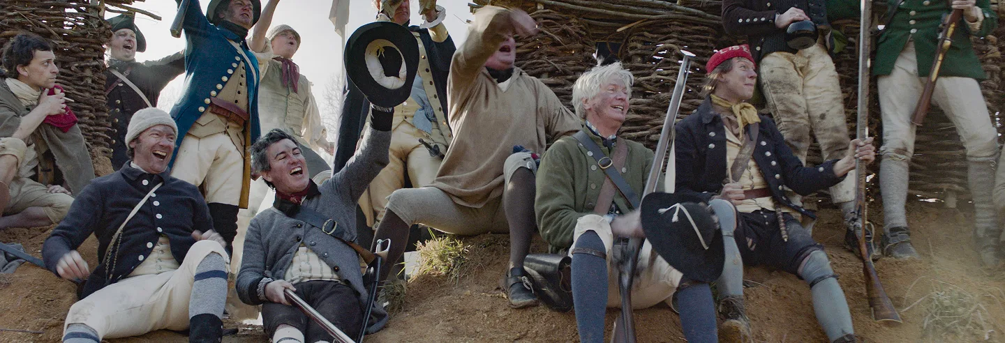 Group of people in historical military uniforms cheering outdoors.