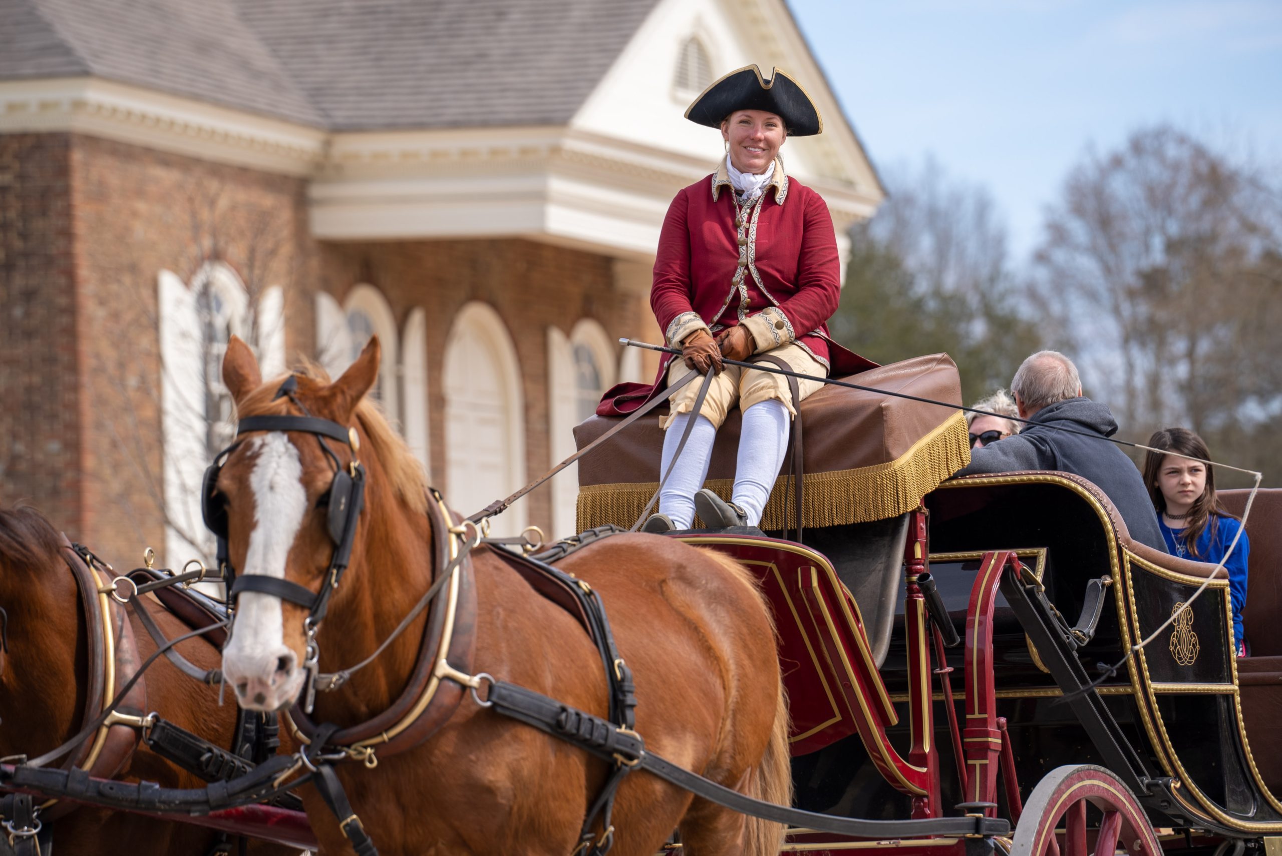 A colonial themed carriage driver smiles on a cool Spring day.